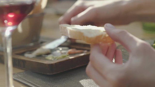 Female hand smearing on bread delicious cheeses and sauces from beautifully served plate in restaurant. Close up