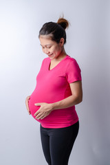Side view midsection of a pregnant woman with hands holding tummy on white background