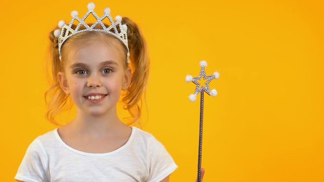 Cute blonde kid waving magic wand and smiling on camera, dreams and childhood