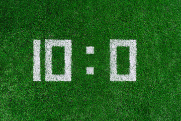 Football score.White numbers ten and zero are drawn on the green grass,creative scoreboard