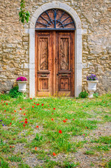 A traditional beautiful wooden door and a window of an old building with some colorful flower pots in spring in Galaxidi Greece