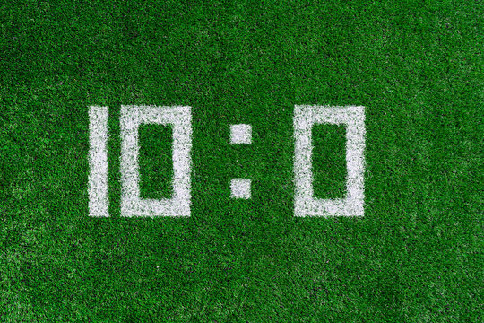 Football score.White numbers ten and zero are drawn on the green grass,creative scoreboard