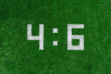 Football score.White numbers four and six are drawn on the green grass,creative scoreboard