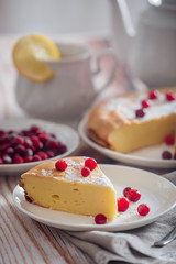 Cheesecake with cranberries and sugar, green tea and lemon on wooden table