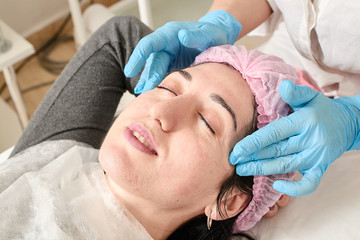 Young woman does professional facial massage after moisturizing, softening, regenerating,...