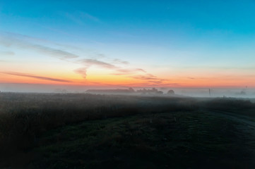 early morning, the sky in the color of dawn before sunrise, field covered with morning mist