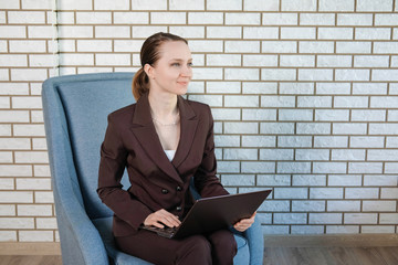 The female model uses a laptop in the office.