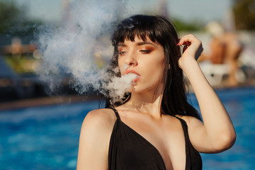 Close-up Portrait of sexy young (vaping) girl in pool. Vapor concept. Vaping e-Cigarette.