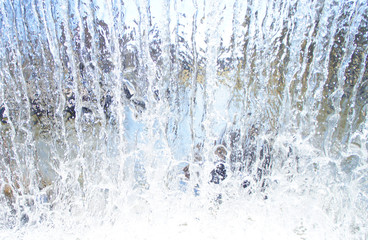Obraz na płótnie Canvas Transparent blue white water pours from above. View through the water wall of the waterfall for the background.