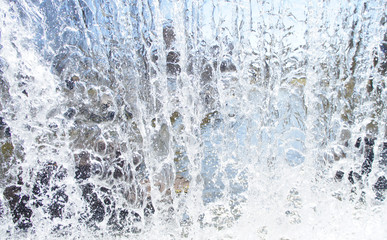 Plakat Transparent blue white water pours from above. View through the water wall of the waterfall for the background.