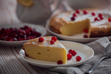 Cheesecake with cranberries and sugar, green tea and lemon on wooden table