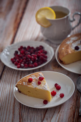 Cheesecake with cranberries and sugar, green tea and lemon on wooden table