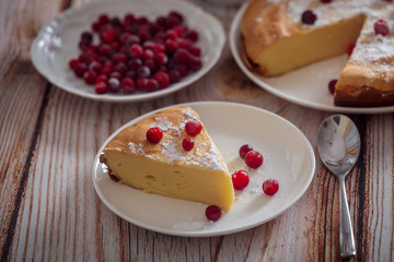 Cheesecake with cranberries and sugar, green tea and lemon on wooden table