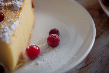 Cheesecake with cranberries and sugar, green tea and lemon on wooden table