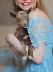 chica con cabrita bebé en sus manos con una sonrisa, tierna cria de animal bebe