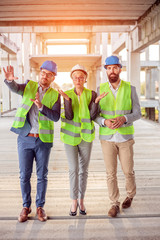 Team of successful young architects and business partners checking work progress on a construction site. Architecture and teamwork concept.
