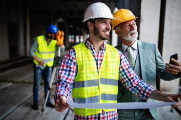 Team of architects and engineer in group on construciton site check documents and business workflow