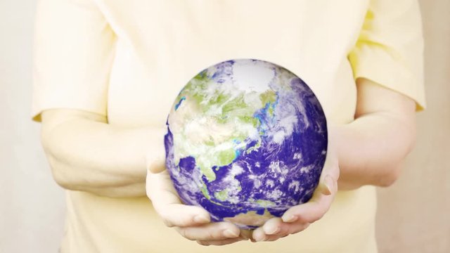 An elderly woman holds a realistic Earth. Element of this video furnished by NASA