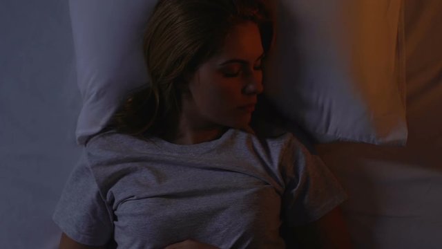 Woman tossing and turning in bed, hardly morning wake up, insomnia, top view