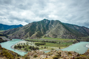 Fototapeta na wymiar Picturesque view on the confluence of two mountain rivers. Katun river and Chuya river against of Altai mountains, Russia. Mountain landscape on a cloudy summer day.