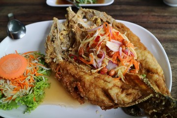 Fired fish with fish-sauce, Snapper topped with sauce, with spicy seafood sauce and vegetable. Thai food.