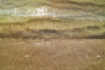 The waves beat at the beach with sand and reflection of sunlight in summer morning. Nature background concept.