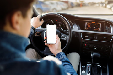 Young business man with phone in car. Man holding smartphone with blank screen .