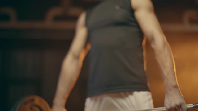 Muscular powerlifter holding barbell, winking and looking around