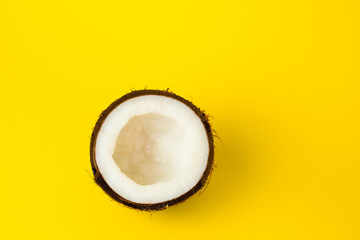 Half of Coconut on yellow colored background, flat lay, top view