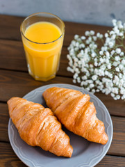 delicious breakfast with croissants, flowers and juice, good morning. Glass of refreshing orange fruit juice