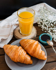 delicious breakfast with croissants, flowers and juice, good morning. Glass of refreshing orange fruit juice