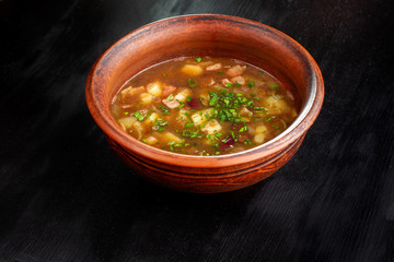 Lentil soup in a bowl on wooden black background.