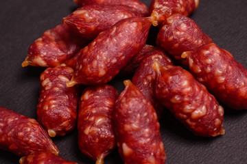 Snack to beer. Small sausages to frothy drink. Background of sausages on a dark background close-up.