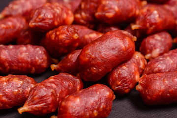 Snack to beer. Small sausages to frothy drink. Background of sausages on a dark background close-up.