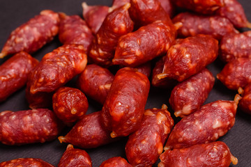 Snack to beer. Small sausages to frothy drink. Background of sausages on a dark background close-up.
