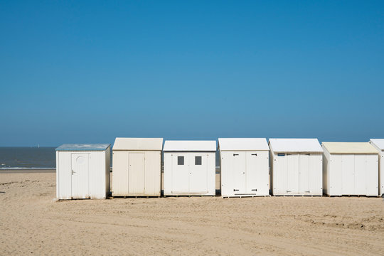 row white beach houses, cabines in Blankenberg, Belgium, against blue sky. Space for text
