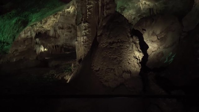 girl photographer with a camera in her hands stands in a gothic mystical gorge, background and location for video and fantasy-style photos, a lady in a cold stone cave with bright color backlighting