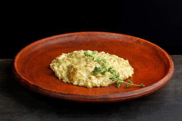 Wheat porridge on a black background in a clay plate.