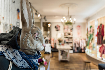 Easter decor with sweet rabbit, blurred background with interior of a shop selling clothes and accessories