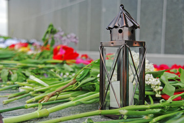 Metal lamp with candle and flowers on the day of remembrance and sorrow