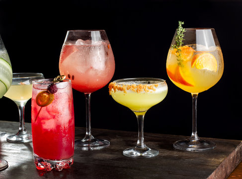 Four alcoholic cocktails with orange slices, ice, watermelon slices, cherries, pears and cucumbers.