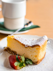 slice of cheesecake with strawberry on brown background, selective focus. A cheesecake pastry in a dish and coffee or tea cup.