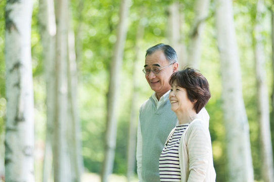 森林の中で微笑むシニア夫婦