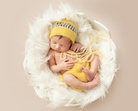 funny sleeping baby in yellow romper on round cot
