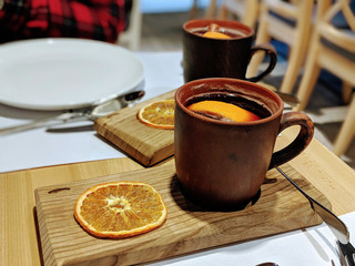 Aromatic mulled wine in ceramic mugs with fresh lemon, cinnamon and candied orange slices, delicious warm drink, cocktail