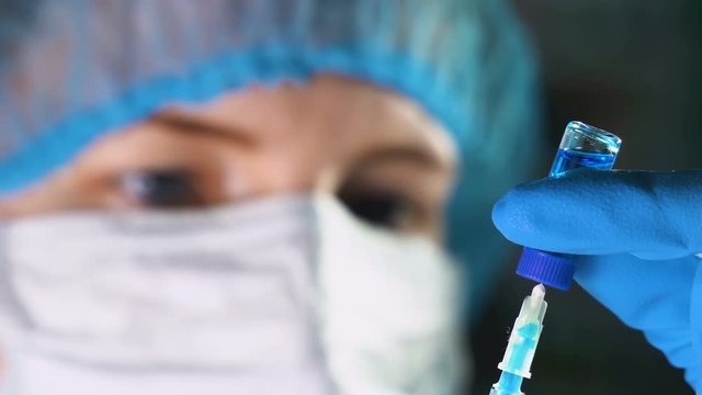 Female doctor picking up medication into a syringe and prepares it for injection.