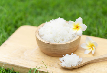 Fototapeta na wymiar Close up white rice in wooden bowl with green nature background, healthy food, selective focus