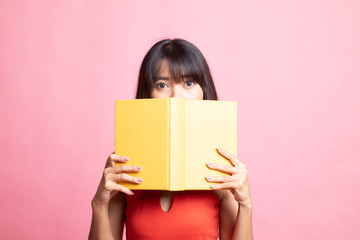 Young Asian woman with a book cover her face.