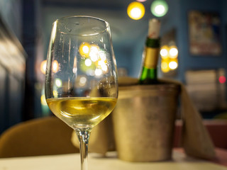 Zbliżenie szczegół szkło Alzacki Reisling biały wino przy romantyczną restauracyjną kolacją. Płytki fokus, wiadro i schłodzona butelka w tle. Colmar, Francja. Podróże i kuchnia. - 262511364