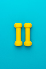 photo of yellow fitness dumbells over blue backgound with central composition